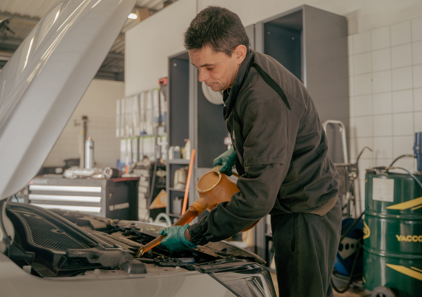 homme du garage CDLA qui met de l'huile dans le moteur d'un véhicule